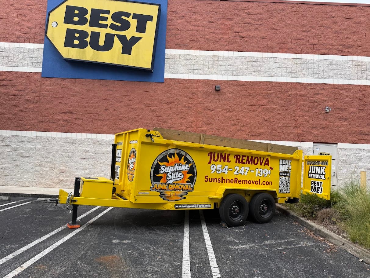 Yellow dump trailer parked in front of a Best Buy store wall and sign